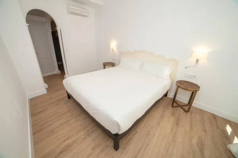 Une chambre lumineuse avec un lit double et des tables de chevet.