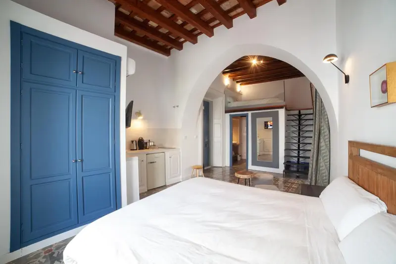 Une chambre lumineuse avec un lit blanc et un espace détente.