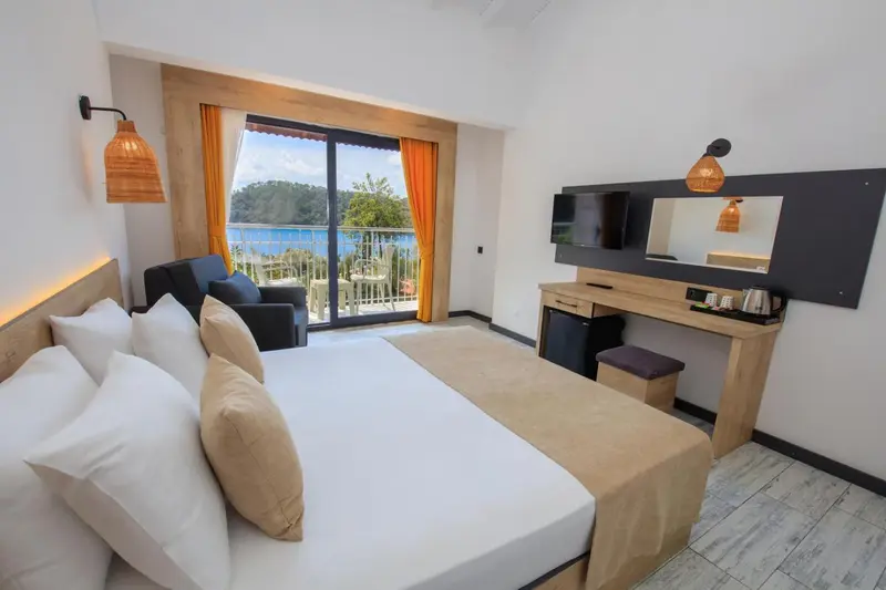 Chambre lumineuse avec un grand lit et vue sur la mer.