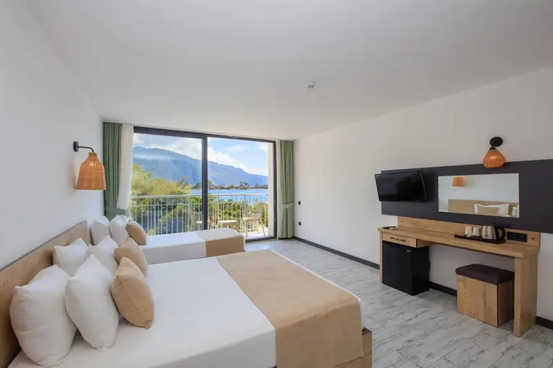 Chambre lumineuse avec un grand lit et vue sur la mer.