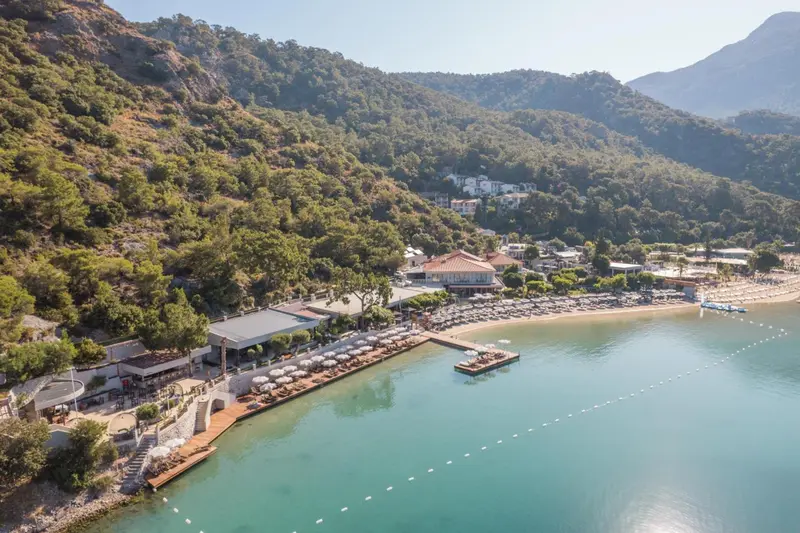 Vue aérienne d'une plage avec des transats et un ponton en bois.