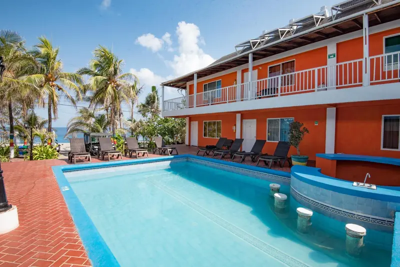 Bâtiment orange à deux étages avec piscine et chaises longues.