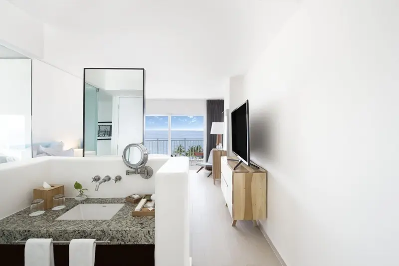 Une baignoire et un lavabo dans une salle de bain lumineuse avec vue sur la mer.
