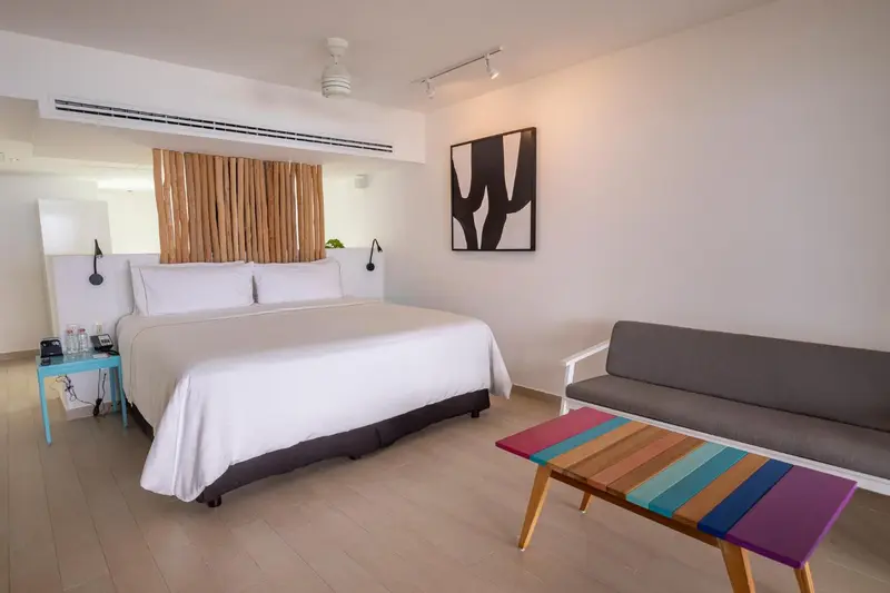 Une chambre lumineuse avec un grand lit et un coin salon coloré.