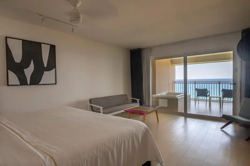 Une chambre lumineuse s'ouvre sur une terrasse avec vue sur la mer.