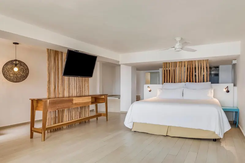 Une chambre lumineuse avec un grand lit et un meuble bas.