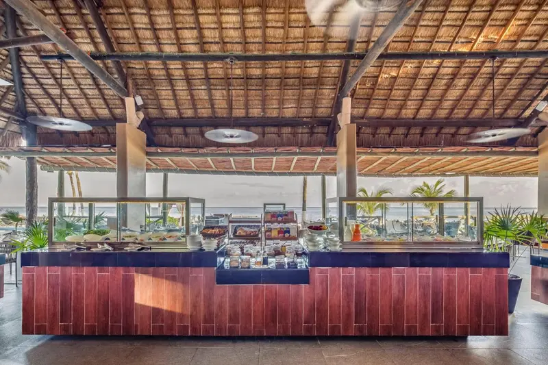 Un buffet propose une variété de plats dans un espace ouvert sur la mer.