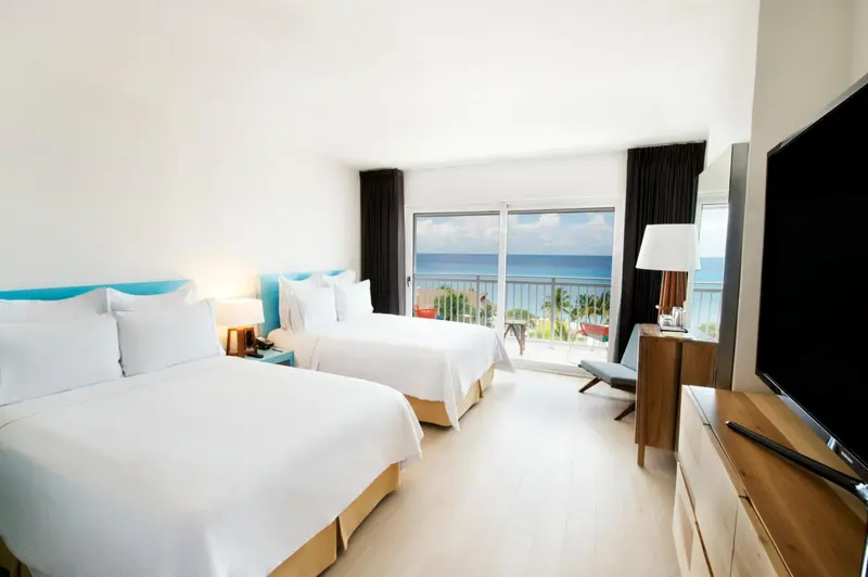 Chambre lumineuse avec deux lits et vue sur la mer.