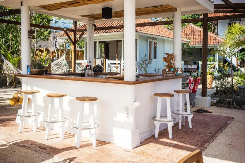 Un bar en plein air avec des tabourets en bois et un comptoir blanc.