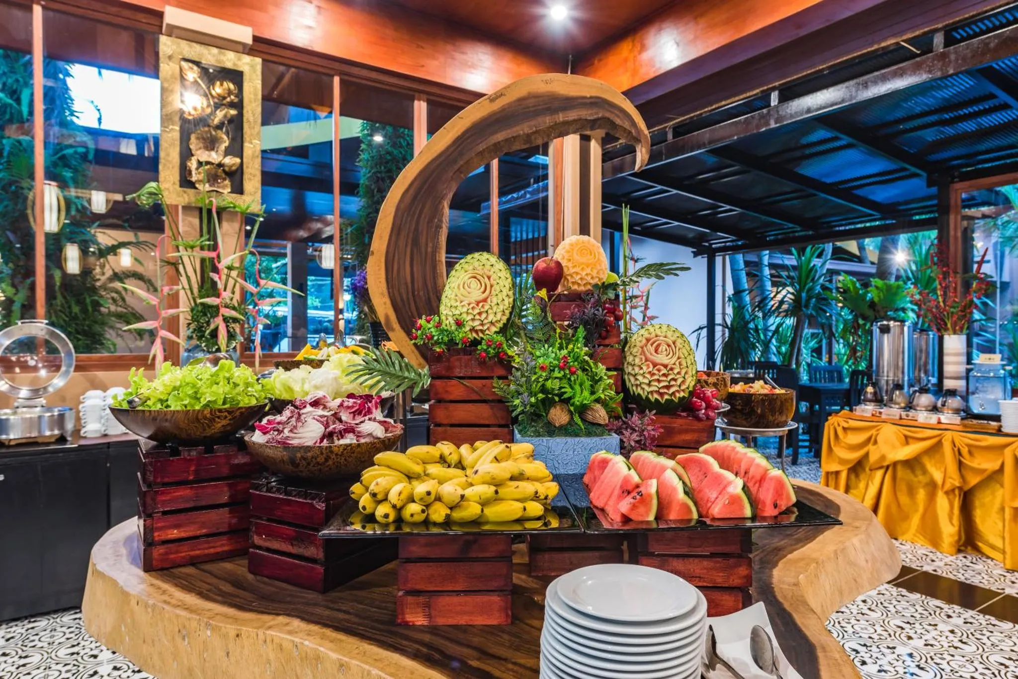 Un buffet généreux de fruits et de salades est présenté dans un espace lumineux et décoré.