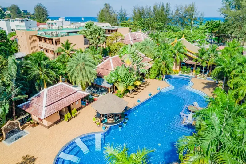 Vue aérienne d'un complexe hôtelier avec piscine et végétation tropicale.