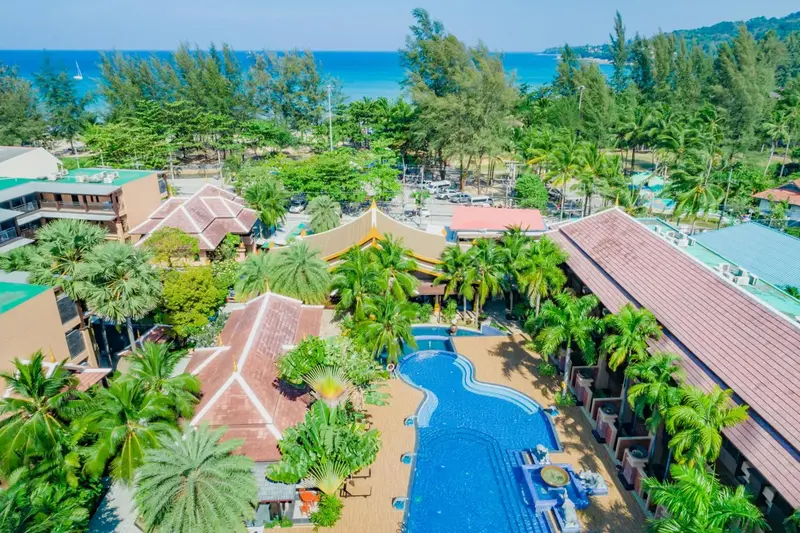 Vue aérienne d'un complexe hôtelier avec piscine et végétation tropicale.