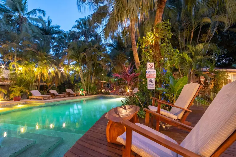Transats et table basse en bois au bord d'une piscine illuminée.