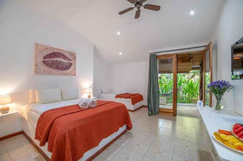 Une chambre lumineuse avec un lit double et un accès à une terrasse.