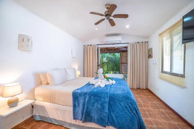 Une chambre lumineuse avec un grand lit recouvert d'une couverture bleue.