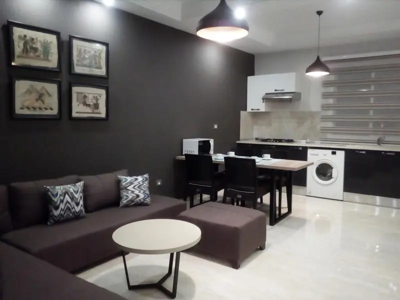Un espace de vie moderne avec un canapé, une table basse et une cuisine équipée.