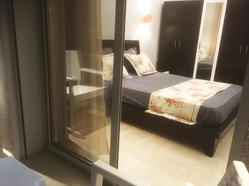 Une chambre avec un lit recouvert d'une courtepointe florale et une terrasse avec des chaises.