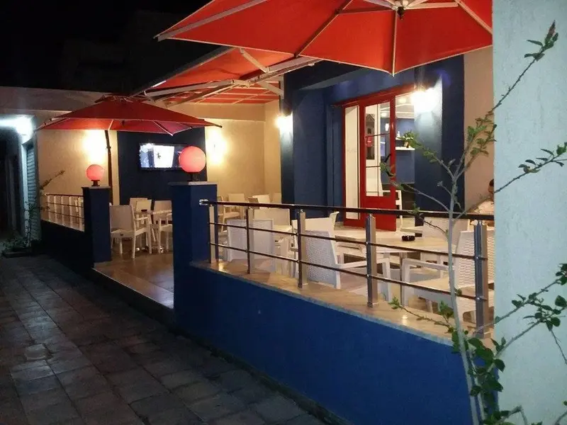 Terrasse ombragée avec tables et chaises blanches.