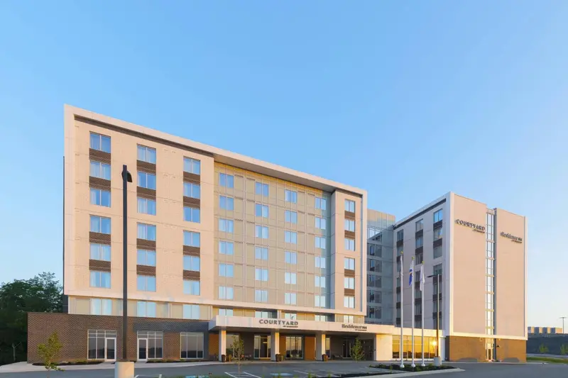 Bâtiment moderne à plusieurs étages avec un parking et des arbres en arrière-plan.