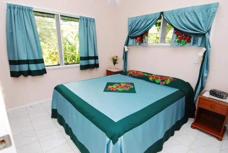Une chambre lumineuse avec un lit recouvert d'une courtepointe colorée et des rideaux assortis.