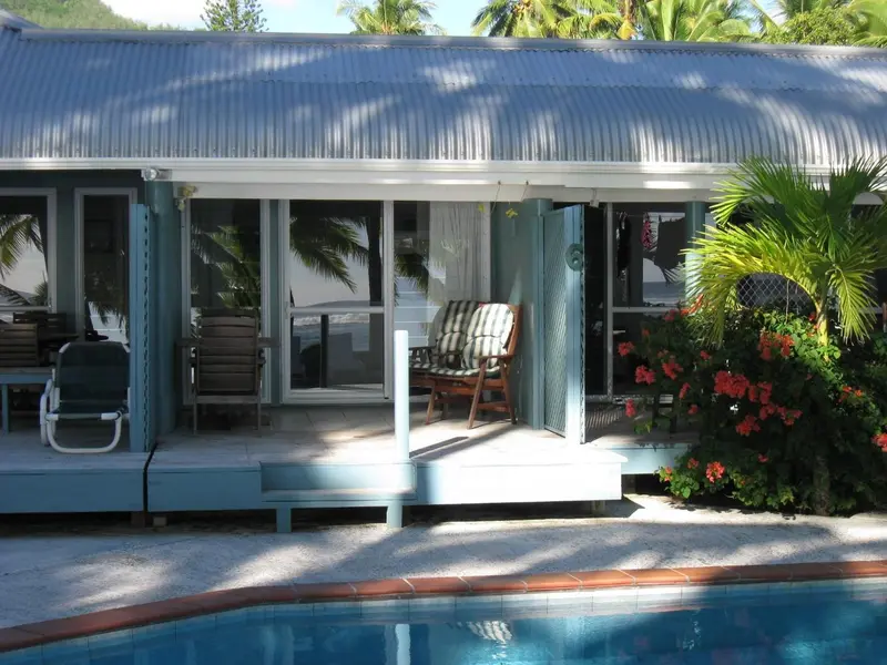 Terrasse ombragée avec mobilier de jardin donnant sur une piscine.