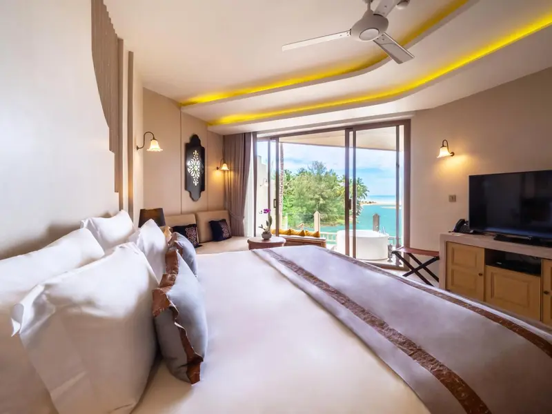 Une chambre lumineuse avec un grand lit donnant sur une vue mer.