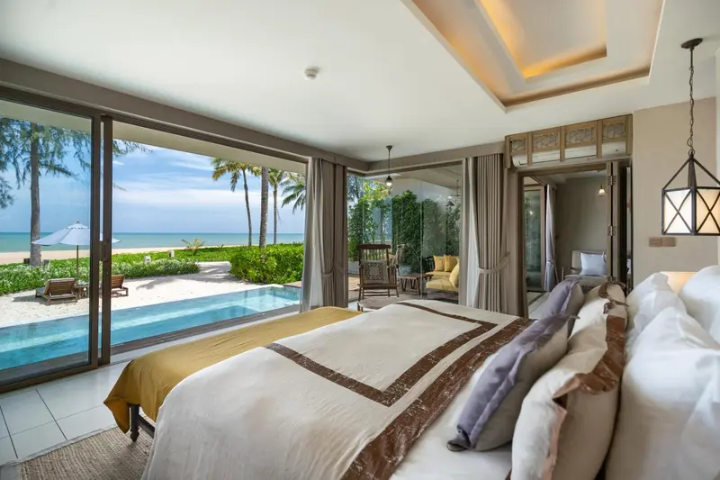 Une chambre lumineuse s'ouvre sur une terrasse avec piscine et vue sur la mer.