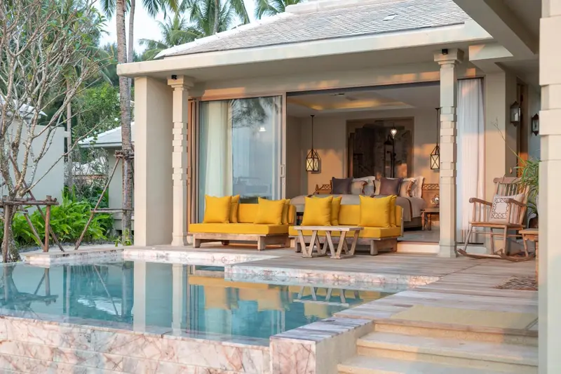 Terrasse avec espace de repos et piscine privée devant une chambre ouverte.