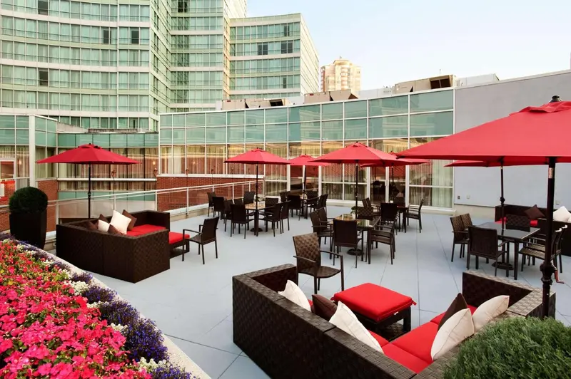 Terrasse aménagée avec des salons et des tables, devant un bâtiment moderne.