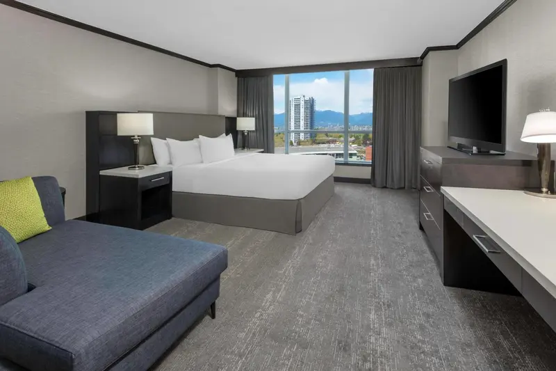 Chambre moderne avec un grand lit et une vue sur la ville.