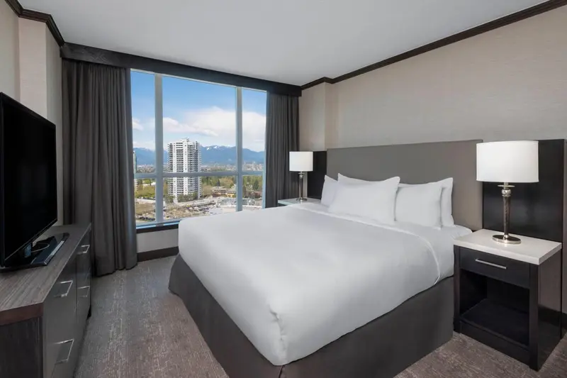 Une chambre d'hôtel lumineuse avec un grand lit et une vue sur la ville.