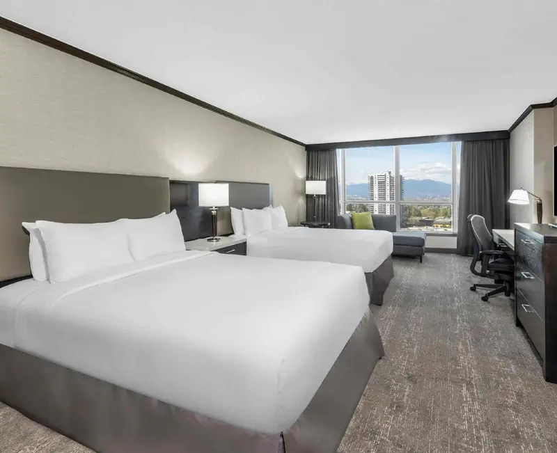 Une chambre d'hôtel lumineuse avec deux lits et une vue sur la ville.