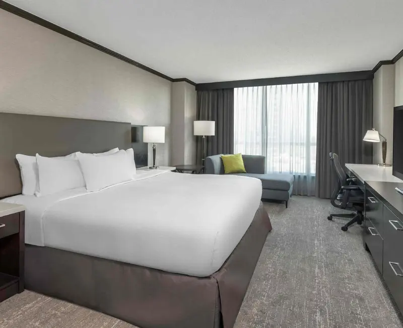 Une chambre d'hôtel lumineuse avec un grand lit et un espace bureau.