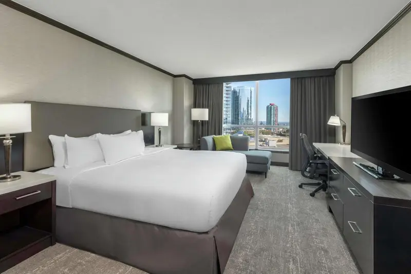 Une chambre d'hôtel lumineuse avec un grand lit et un coin salon près d'une fenêtre.