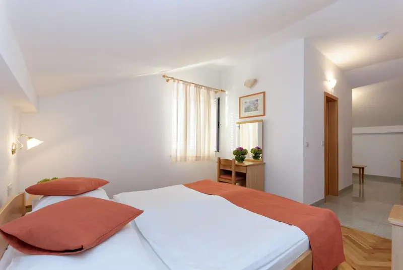 Chambre lumineuse avec deux lits simples et une coiffeuse.