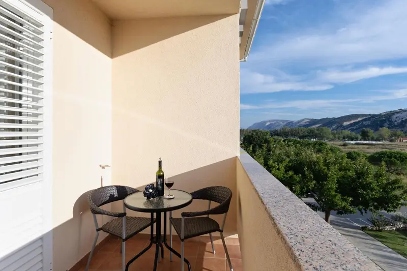 Une petite table ronde avec deux chaises sur un balcon ensoleillé.