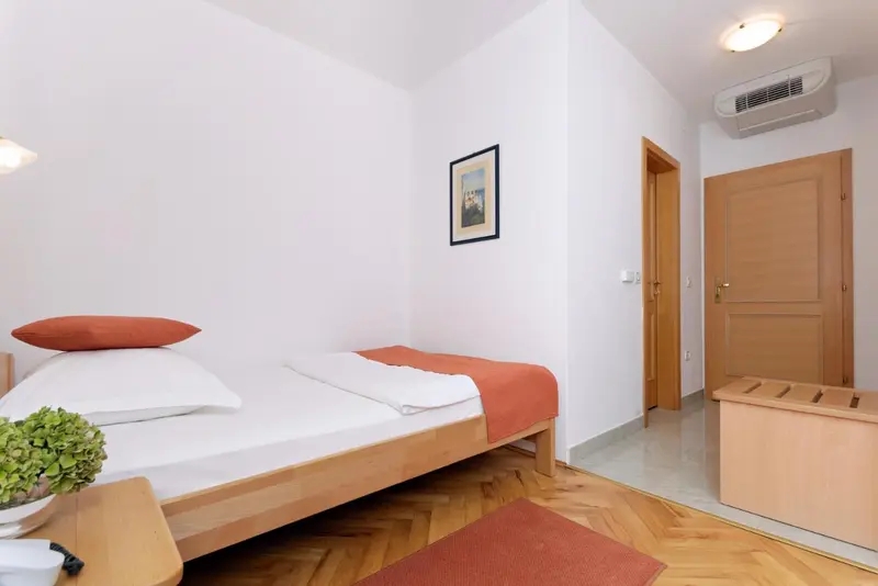 Une chambre lumineuse avec un lit simple et un parquet clair.