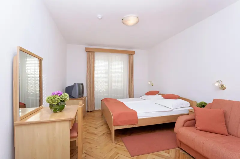 Une chambre lumineuse avec un lit double et un coin salon.