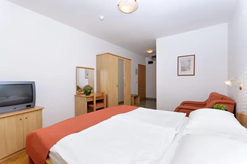 Une chambre lumineuse avec un lit double et un meuble de télévision.