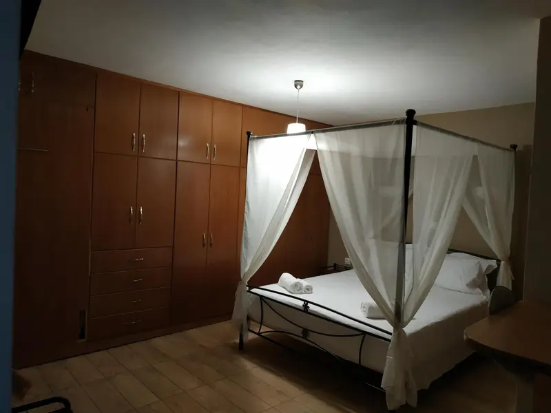Une chambre lumineuse avec un lit à baldaquin et de grandes armoires en bois.