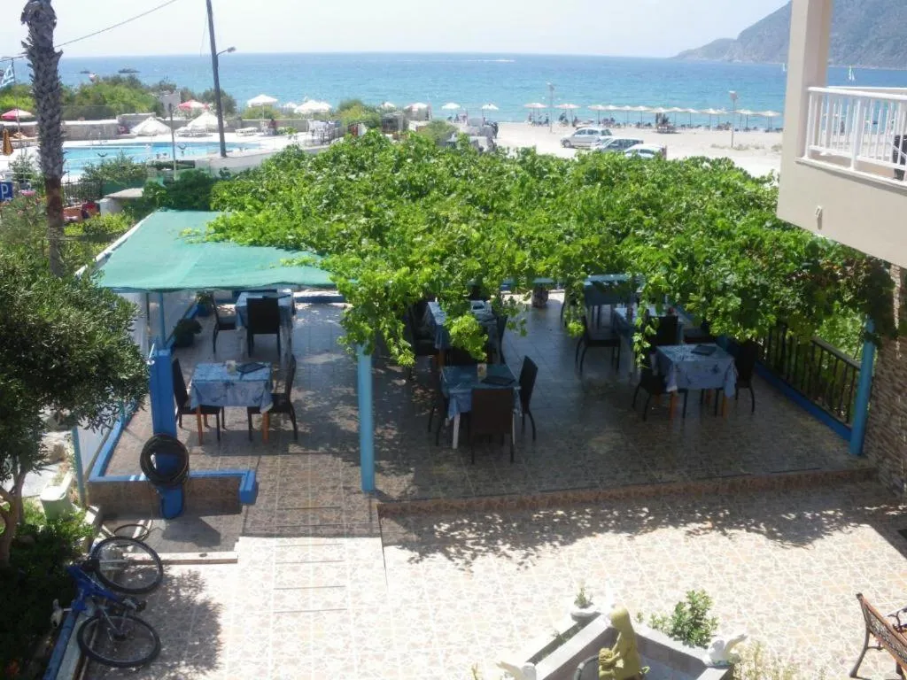 Terrasse ombragée avec tables et chaises près d'une piscine et d'une plage.
