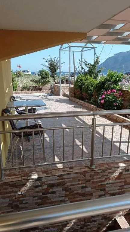 Terrasse ombragée avec mobilier de jardin et vue sur la mer.