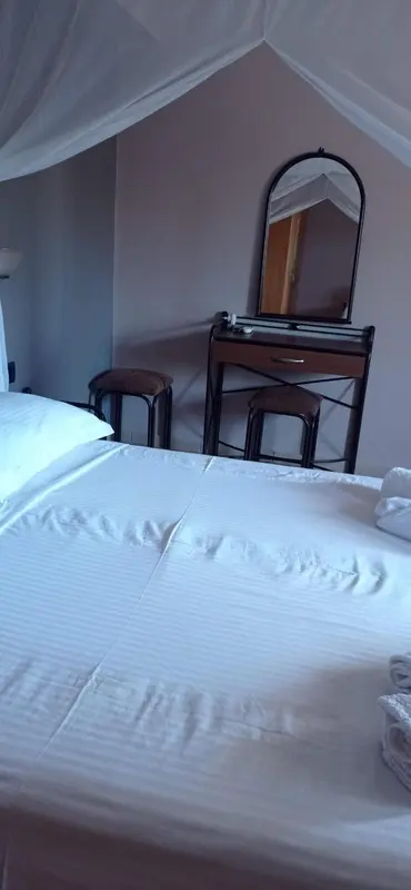 Une chambre lumineuse avec un lit fait et une coiffeuse.