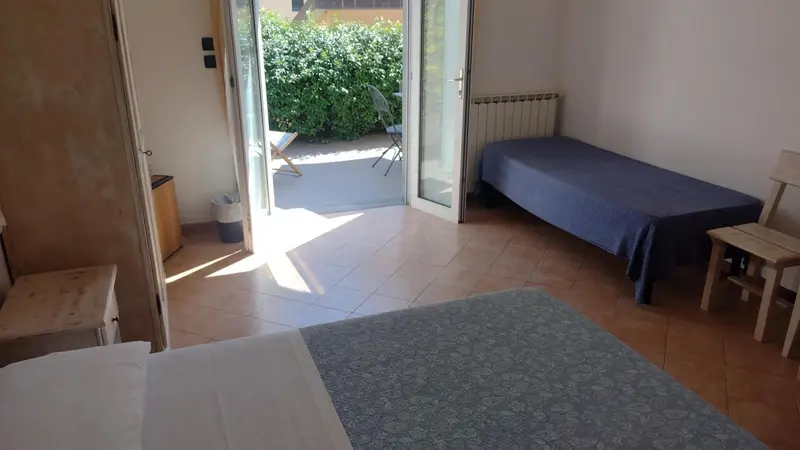 Une chambre lumineuse s'ouvre sur une terrasse ensoleillée.