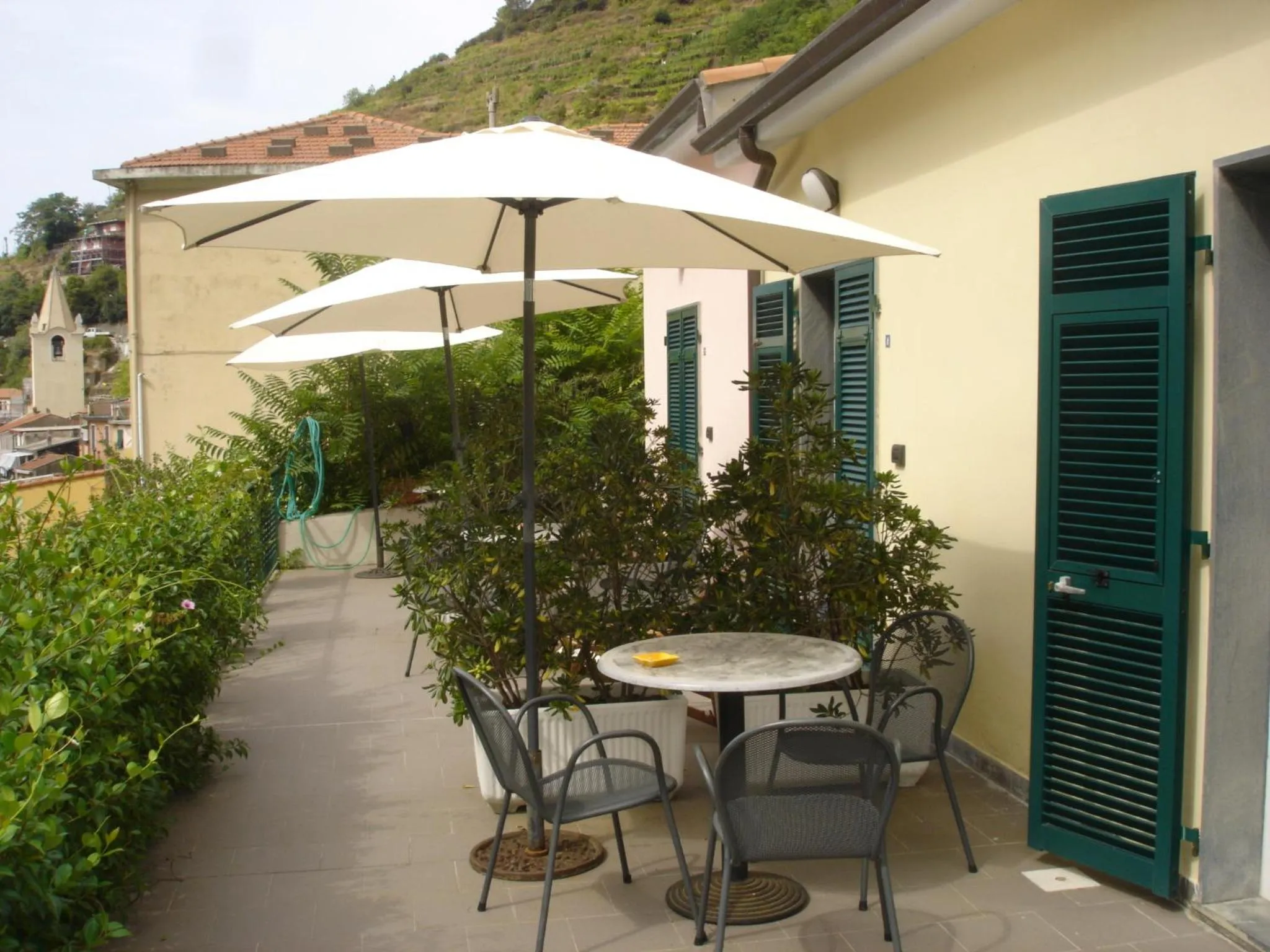 Terrasse ombragée avec tables et chaises en métal.