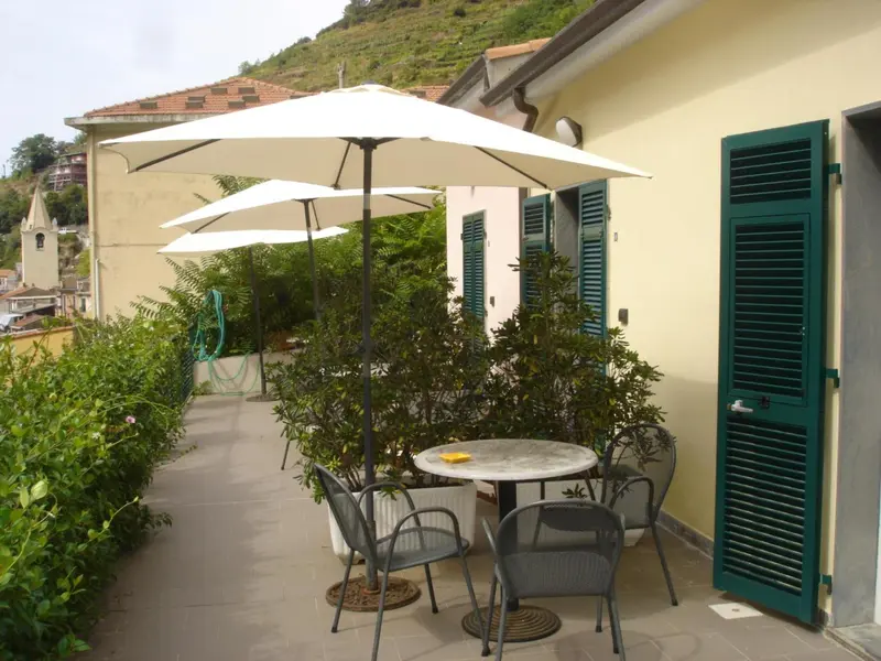 Terrasse ombragée avec tables et chaises en métal.
