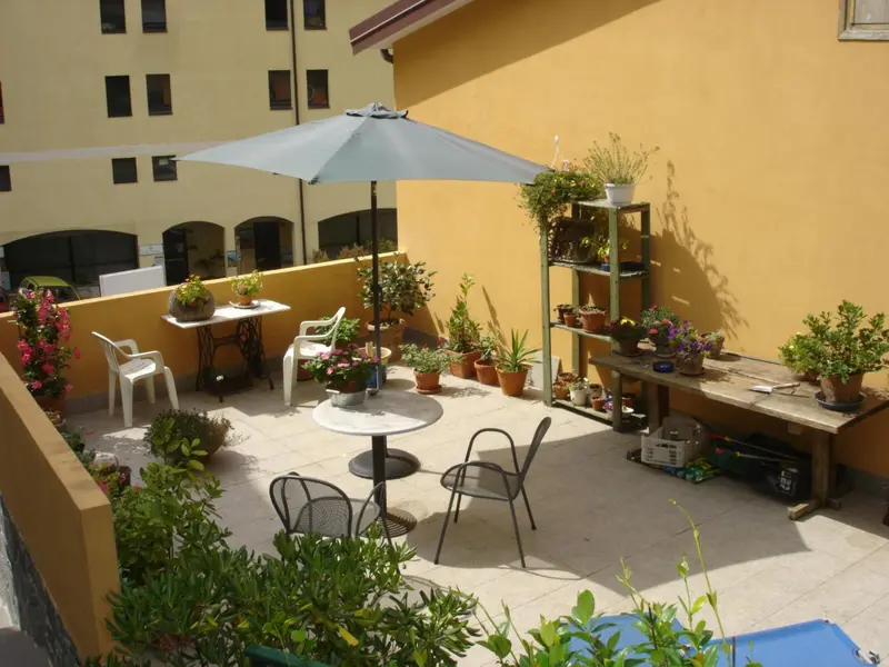 Terrasse fleurie avec mobilier de jardin et plantes en pot.