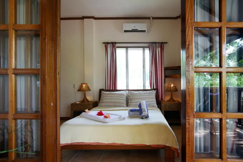 Une chambre lumineuse avec un lit double et des meubles en bois.