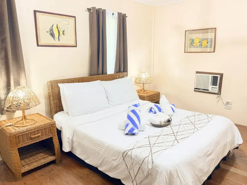 Une chambre lumineuse avec un grand lit recouvert d'une courtepointe blanche et de décorations.
