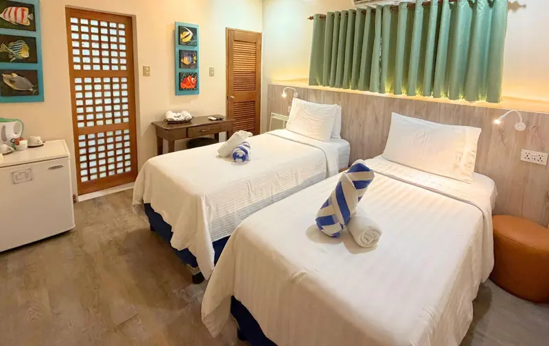 Une chambre lumineuse avec deux lits simples et une décoration marine.